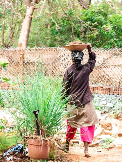 A woman carries a basin of mud on her head, a common sight on a natural building site. This image represents the hard work and determination of the women we work with.