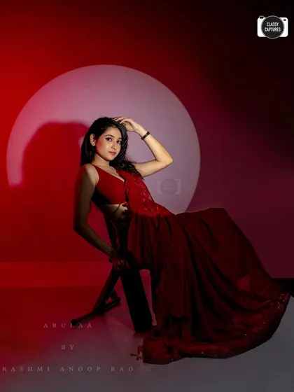 A dramatic shot of the red saree-gown. The lighting creates a powerful mood, highlighting the bold color and silhouette of the outfit.