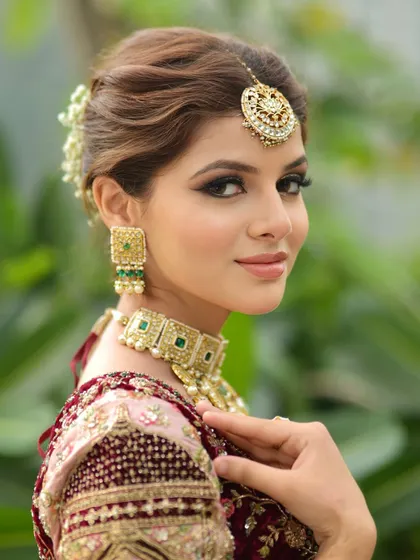 A classic bridal portrait. I created a soft glam look with defined eyes and a neutral lip color to complement her ornate jewelry and pastel lehenga. The hair is styled in an elegant bun adorned with fresh flowers.