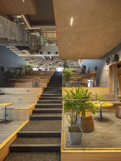 A view from the base of the atrium at Primarc shows how the terraced design creates inviting pockets for pause and conversation. This unconventional layout balances focused work with social interaction, ensuring the space feels deeply human.