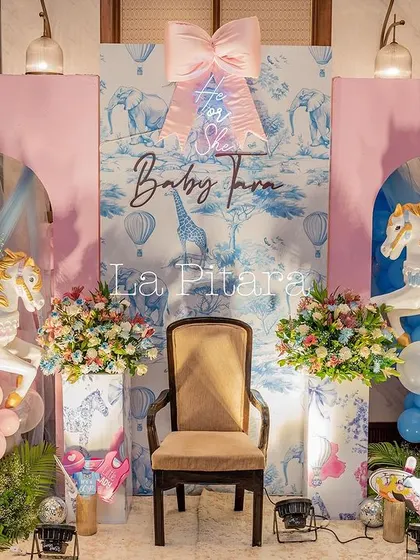 The main stage for the Baby Dior shower, featuring a throne chair, carousel horses, and a backdrop that combines the pink and blue color scheme.