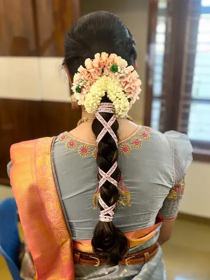 An intricate braid with a pink and white ribbon criss-cross pattern, topped with a custom floral arrangement.