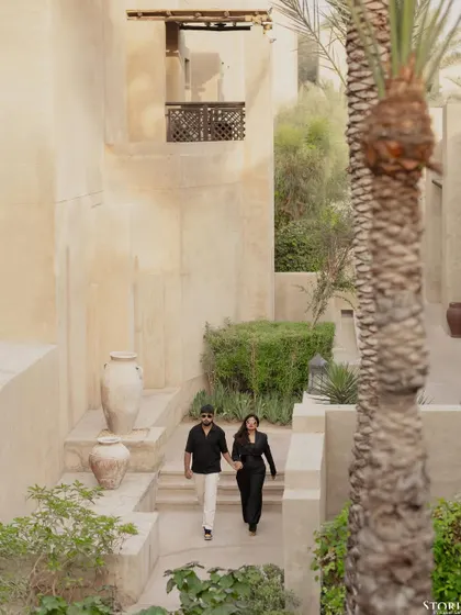 Capturing a candid moment as the couple walks through the beautiful, sand-colored architecture of a Dubai resort. This image tells a story of a shared journey in an exotic location.