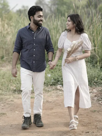 A happy couple walks hand-in-hand down a country path, the bride holding a small bouquet, creating a lovely, candid photo.