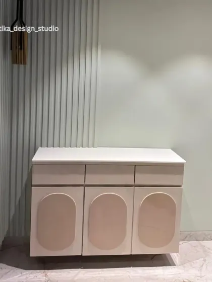 A close-up of the custom console table with its unique rounded-panel doors. This piece provides discreet storage and is set against a textured fluted wall, adding depth and interest to the narrow space.