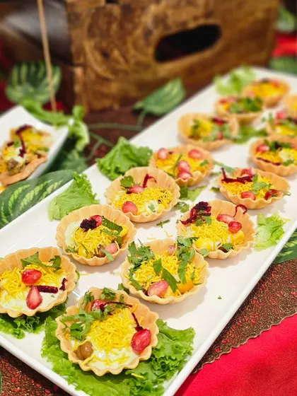 These delicious chaat tarts are a creative and tidy way to serve chaat at a hi-tea event. They are filled with savory toppings and yogurt, offering a burst of flavor in every bite.