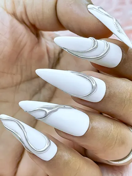 A different angle of the white and silver chrome nails, showing how the metallic lines curve and wrap around the nail.
