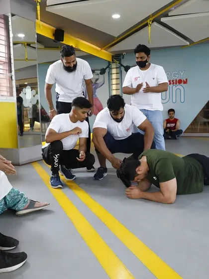 The final moments of a plank hold are a mental and physical battle. Here, fellow members and coaches gather to cheer on a competitor, embodying the spirit of our gym community.
