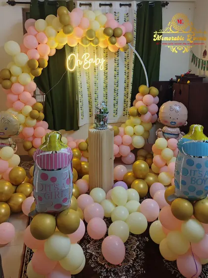 A lovely baby shower decoration with pastel pink and gold balloons, an 'Oh Baby' neon sign, and baby-themed foil balloons.