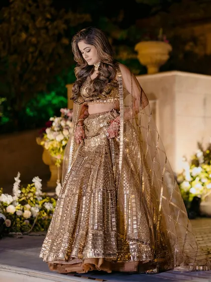 A stunning solo portrait of the bride-to-be in her shimmering golden lehenga, looking every bit the star of the evening.