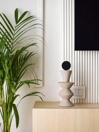 A detail shot of the TV console, with a simple, sculptural decor piece and a large plant adding a touch of nature.