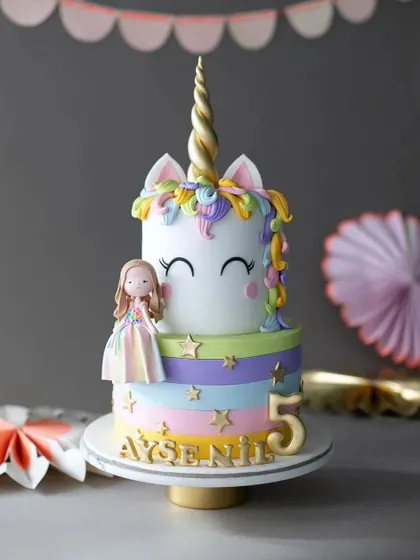 A magical two-tiered unicorn cake for a 5th birthday. This pastel rainbow cake features a cute unicorn topper and delicate star details.