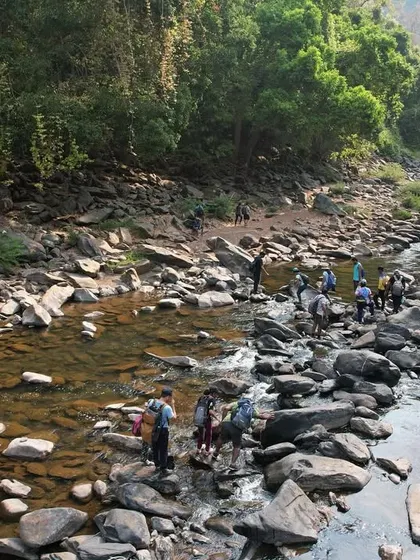 A group crossing the Aghanashini river during the summer. The water level is low, making it a fun activity.