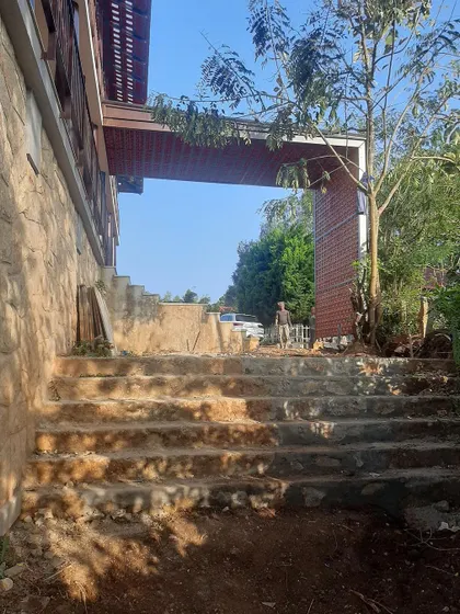 The entrance steps of the guest facility in Chikmagalur, carved from the natural terrain. The design respects the lay of the land, using local stone and materials to create a seamless transition from the landscape to the building.