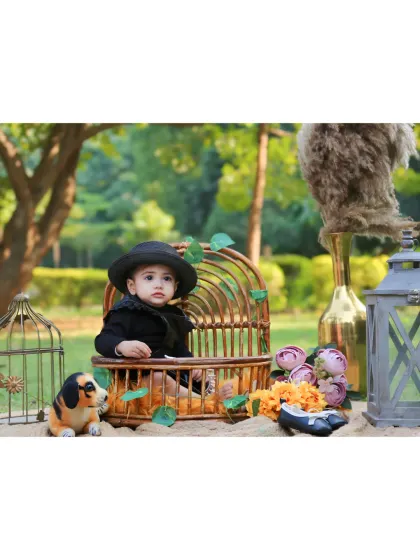An outdoor first birthday shoot with a stylish, rustic theme, featuring a baby in a black hat and outfit.