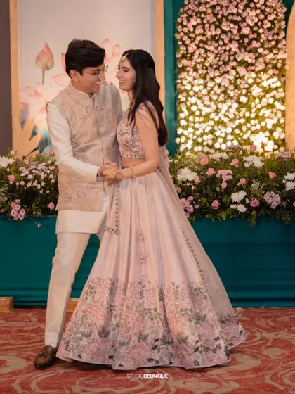 The couple sharing a sweet moment during their dance. The floral wall behind them adds a touch of romance and natural beauty.