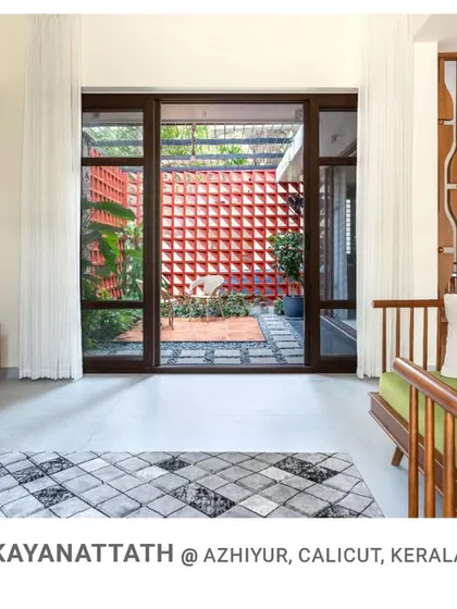 Another angle of the Kayanattath living room, emphasizing the large opening to the courtyard with its distinctive red jali wall, which adds color and texture to the view.