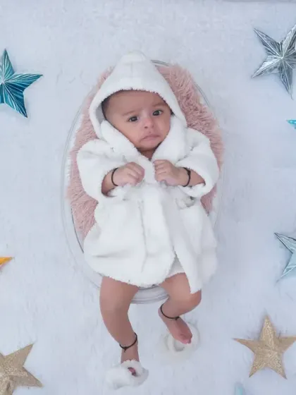 An adorable baby in a tiny white bathrobe surrounded by colorful star props. This is part of my "Up in the Clouds" theme, designed to be soft, dreamy, and cute.