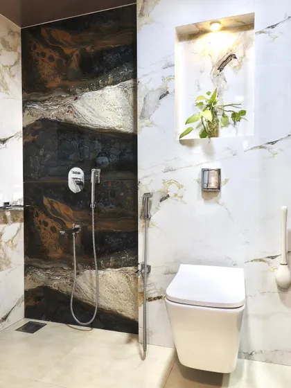 This image shows the shower area next to the toilet, featuring a dramatic, dark-veined marble tile. The consistent use of high-quality materials creates a cohesive and luxurious bathroom space.