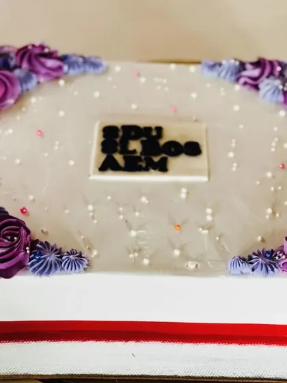A blueberry sheet cake with purple floral corners, perfect for a large gathering.