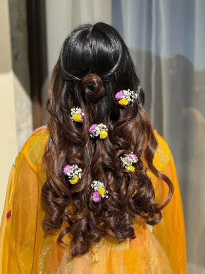 The hairstyle for this look featured soft curls adorned with fresh baby's breath and flowers, adding a romantic and bohemian touch.
