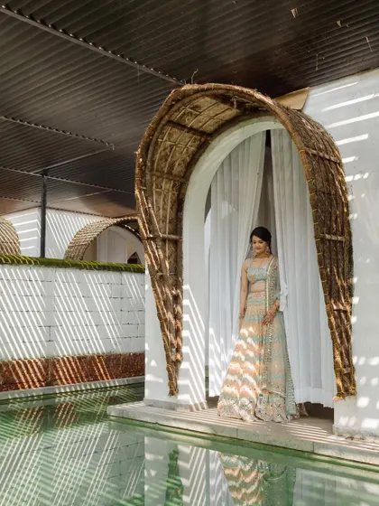 A portrait of the bride at the Taj Bekal resort, framed by the unique, rustic architecture of her villa.