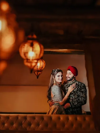 An artistic shot of a Sikh couple sharing a moment, framed by warm, glowing lanterns. This image has a romantic, intimate feel, perfect for an engagement album.