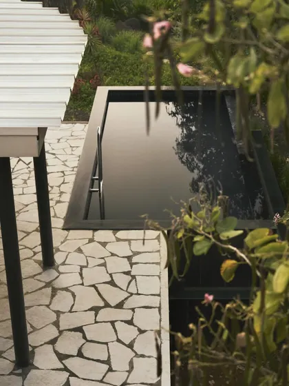 The black mirror-like pool at Pavilion House, an elevated jewel that reflects the architecture and the sky. This feature was a key part of the design, creating a point of still symmetry and a place for quiet contemplation within the natural setting.