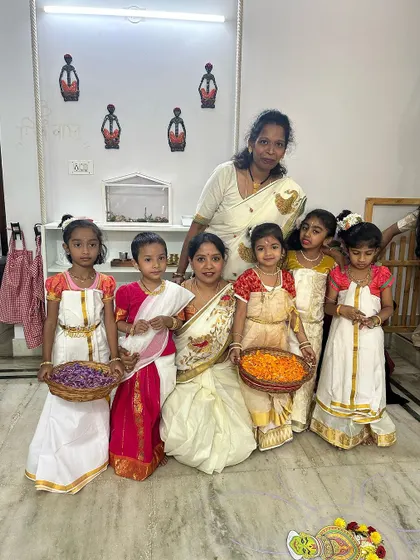 Our wonderful teachers and children dressed in traditional Onam attire, holding baskets of flowers ready for making the pookalam.