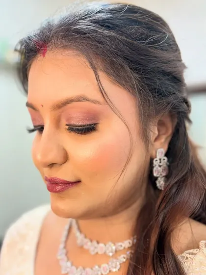 A close-up of a simple yet elegant party makeup look. The focus is on clean skin, soft pink eyeshadow, and a matching lip color.
