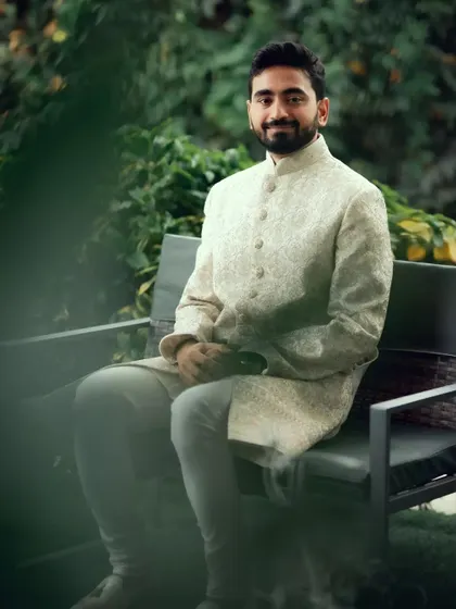 A relaxed portrait of the groom in his elegant sherwani, waiting in a garden before the ceremony.