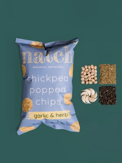 A clean and simple flat-lay for Natch's garlic and herb chips. The product is placed next to its ingredients, making it easy for customers to see what's inside at a glance.