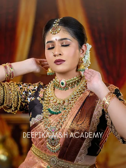 A beautiful portrait of a bride with her eyes closed, highlighting the detailed eye makeup. The look is completed with a stunning choker, layered necklaces, and a traditional maang tikka.