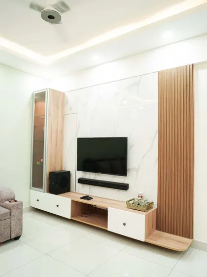 A minimalist TV unit with a light wood console and a marble-finish back panel. The vertical fluted wood accent adds texture and warmth to the clean design.