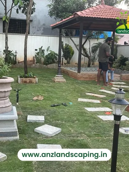 This photo captures our team during the landscaping process. You can see them laying a stone path and working on the garden layout around a newly constructed gazebo, bringing the design to life.