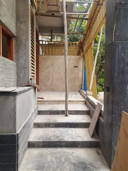 This cozy entryway is taking shape. The design combines different materials like stone, wood, and brick to create a textured and inviting passage that directs focus towards the main living areas.