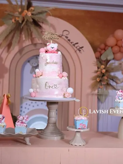 The cake and dessert table from a boho-themed party, featuring a multi-tiered cake and cupcakes all decorated to match the adorable teddy bear concept.