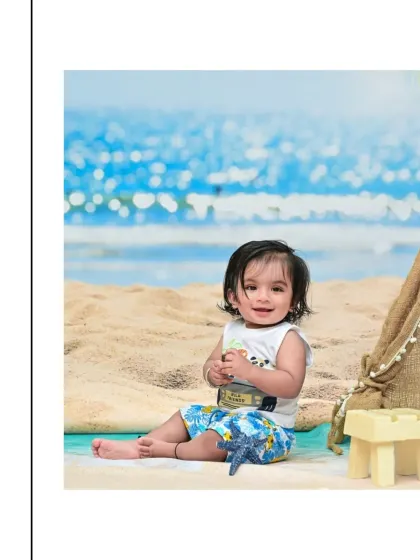 A happy baby boy enjoying a day at the beach in the studio. The sandy floor, ocean backdrop, and starfish prop create a convincing and fun seaside setting for his sitter session.