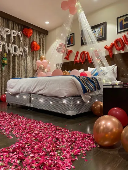 A close-up of the beautifully decorated bed with a fairy light canopy and a pathway of rose petals.