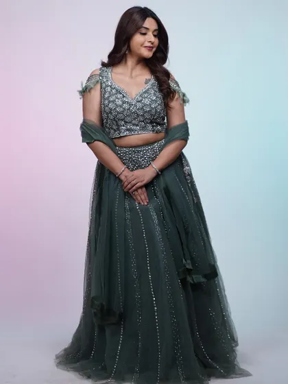 This dark green lehenga combines traditional elegance with a modern twist. The off-shoulder feather detailing on the blouse is a unique touch that sets it apart.