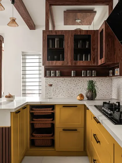 In 'Project Varnika', the U-shaped kitchen is brought to life with vibrant mustard yellow cabinets and a terrazzo dado. I included open wicker basket drawers for easy access to vegetables.