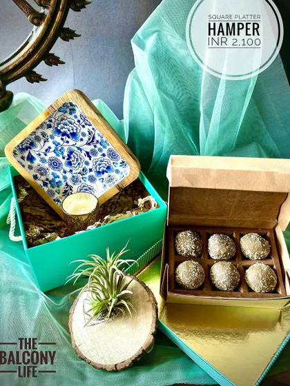 I love how this hamper turned out. The star is the beautiful square platter with its intricate blue and white enamel work, paired with a box of delicious upcycled sweets. We added a little botanical friend, an air plant, nestled in a rustic wood holder to bring a touch of green life to your home.