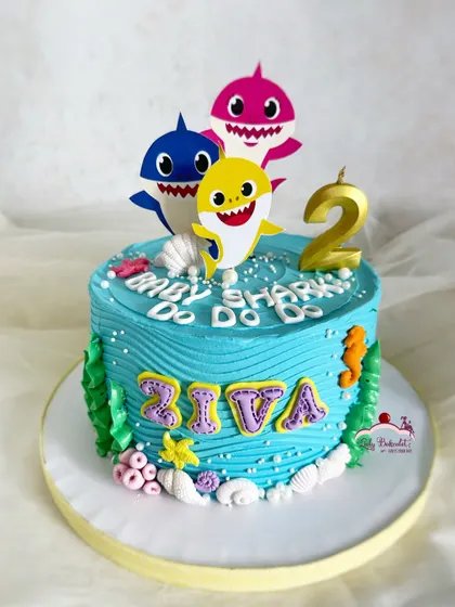 Baby shark, but make it cute! A simple and sweet baby shark cake with edible toppers and a wavy buttercream finish.