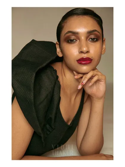 A bold and striking beauty portrait. The slicked-back hair, dramatic makeup, and structural sleeve create a high-fashion, avant-garde look.