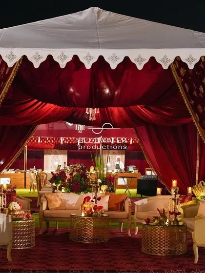 The exterior of the lounge tent, with its traditional scalloped valance and rich red curtains, creating an inviting and regal space for guests.