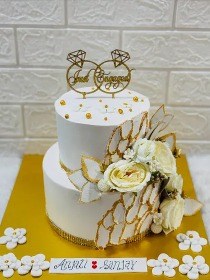 Simple elegance for a special announcement. This two-tiered "Just Engaged" cake features a clean white finish, delicate sugar flowers, and gold accents for a timeless look.
