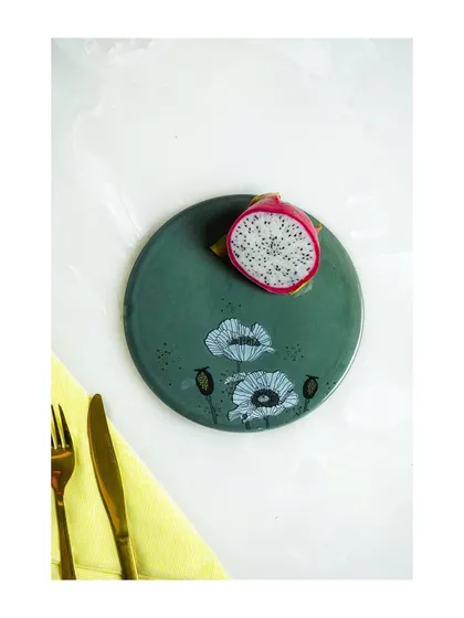 A minimalist, top-down shot of a hand-painted plate with a slice of dragon fruit. The simplicity and use of negative space create a very modern and artistic image.