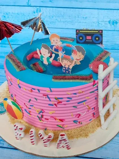 A fun and vibrant pool party themed cake. The design features a "pool" filled with jelly, surrounded by candy and sprinkles, with a sandy beach made of crushed biscuits.