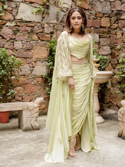 This lime green draped skirt and crop top set on Nushrratt Bharuccha is perfect for a destination wedding. The embroidered cape adds a touch of elegance.