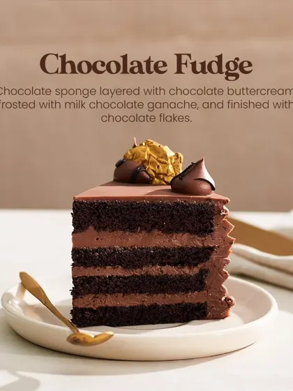 A single, perfect slice of my Chocolate Fudge Cake. This image highlights the four layers of sponge and buttercream, crowned with a chocolate kiss and gold leaf.